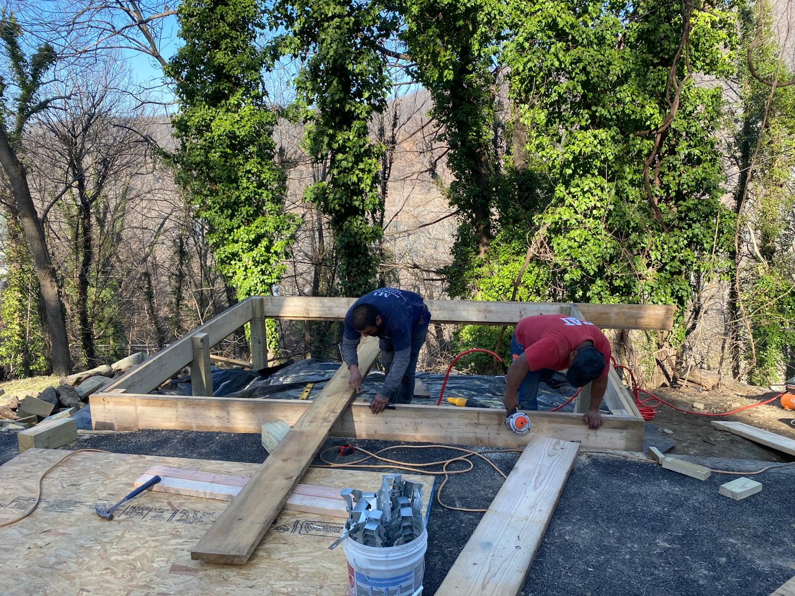 Carpenters framing an exterior deck overlooking forest
