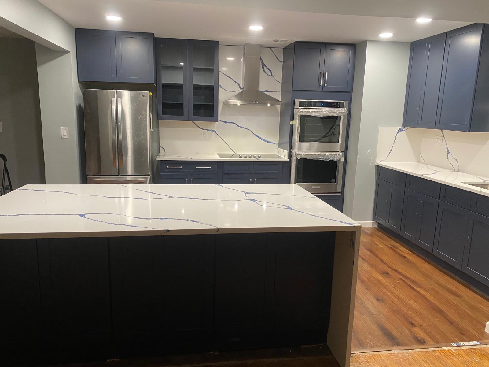 Completed luxury kitchen with navy shaker cabinets and quartz island